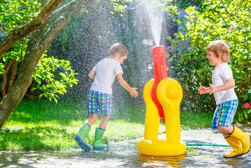 Two boys playing in a sprinkler to manage humidity in Beaufort, NC.