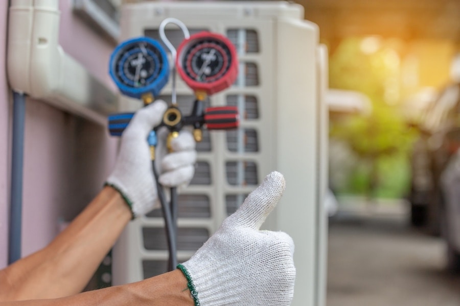 A pair of hands in front of an air conditioning unit.