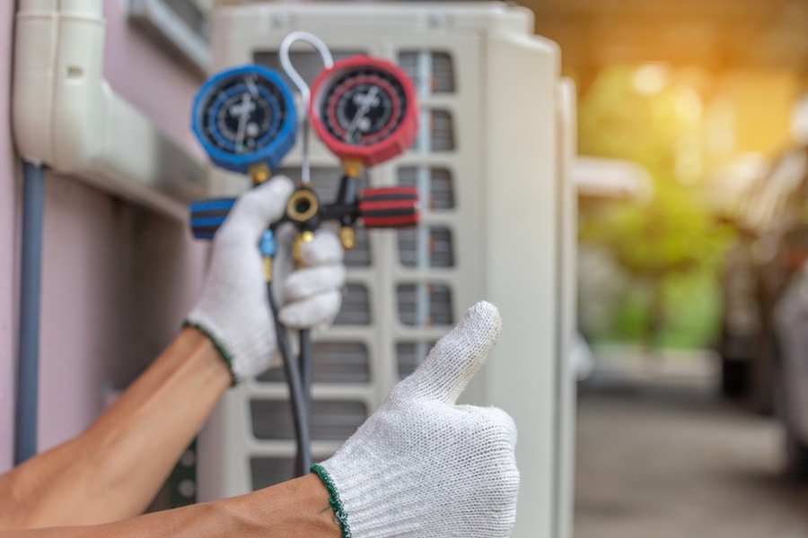 A pair of hands in front of an air conditioning unit