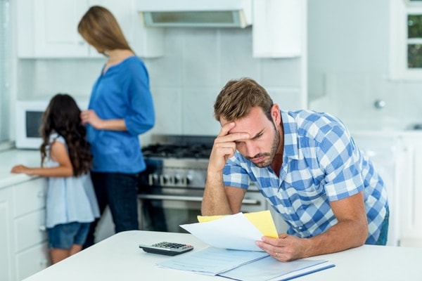 A father hovering over paperwork with a confused and frustrated look on his face.