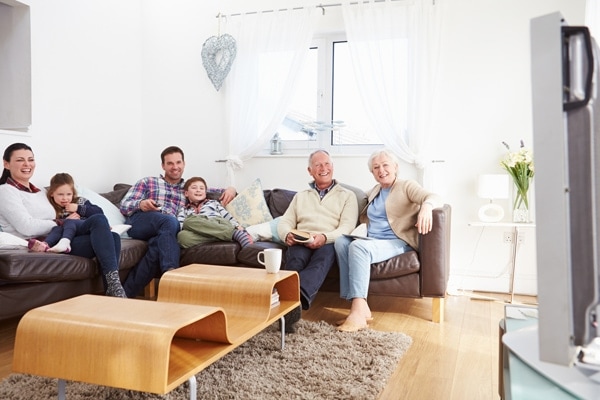 A family sitting around a tv, laughing, wondering about different types of furnaces.