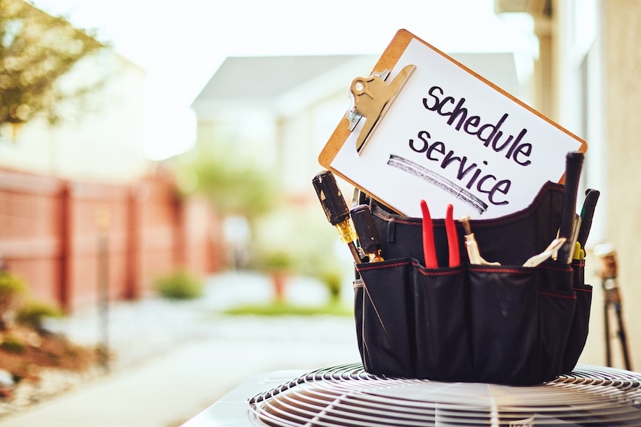 Schedule Service Reminder on clipboard on top of AC unit