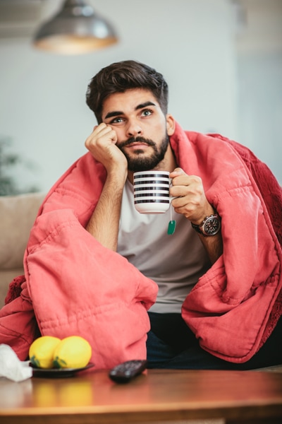 Man wrapped in a blanket to stay warm. Why Isn’t My Furnace Heating My Entire Home?