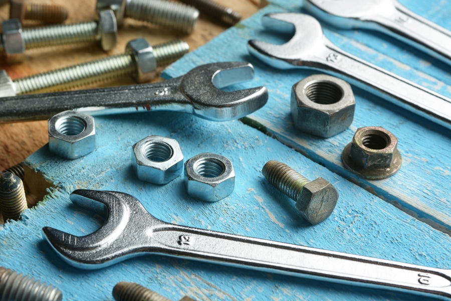 Bolts and english wrenches on wooden table - closeup. Heat pump maintenance tips.