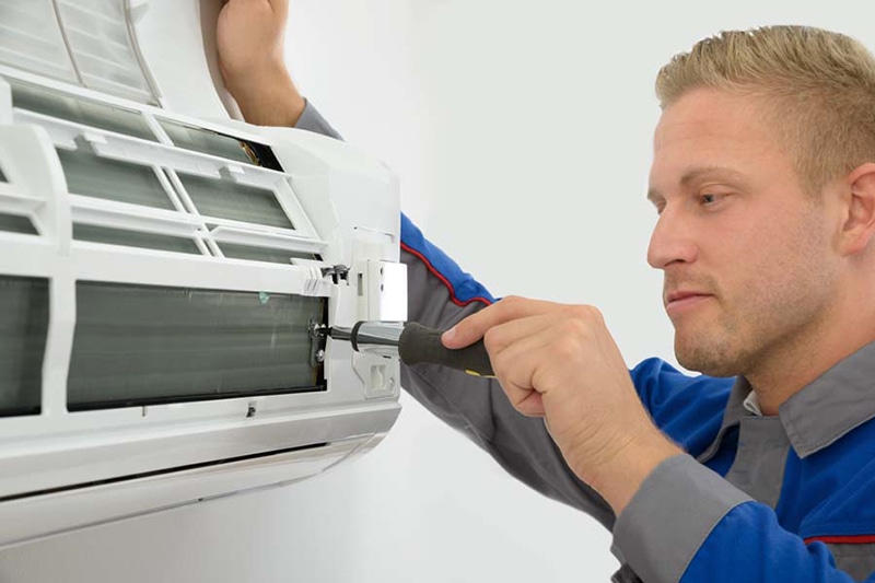 Portrait Of Young Male Technician Repairing Air Conditioner, Do I Really Need an AC Tune-Up?