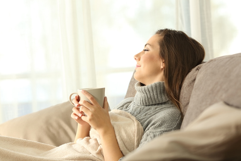 A woman relaxing in a chair with a mug.