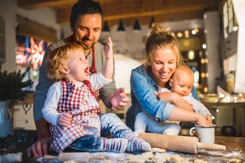 Family indoors getting flour all over as they make cookies.