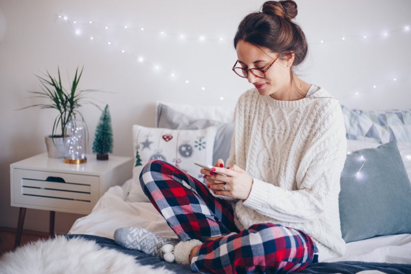 Women on bed texting.