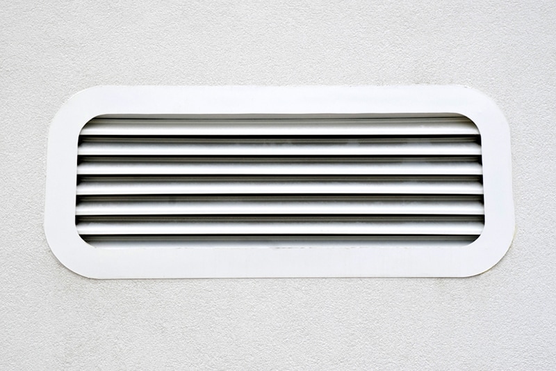 New white air conditioning vent on wall closeup.