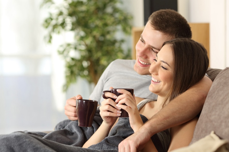 Young married couple smiling while watching television.