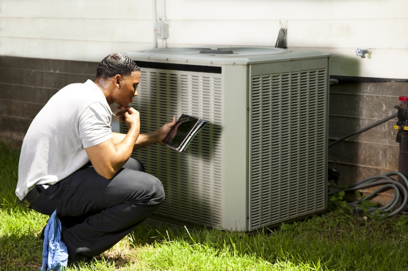 Home inspector, repairman uses digital tablet to check air conditioners.