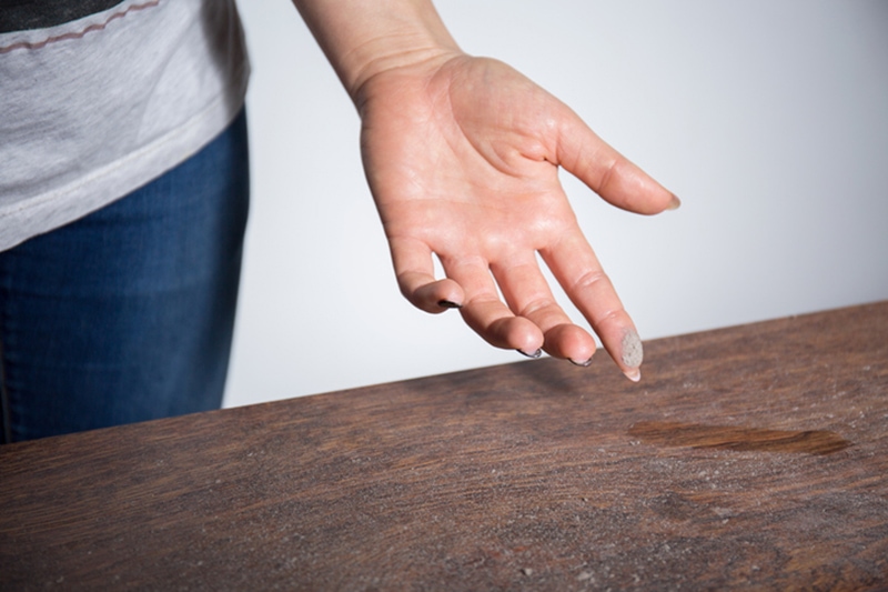 How to Eliminate Dust in My Home, Close-up of dust on woman finger taken from wooden table