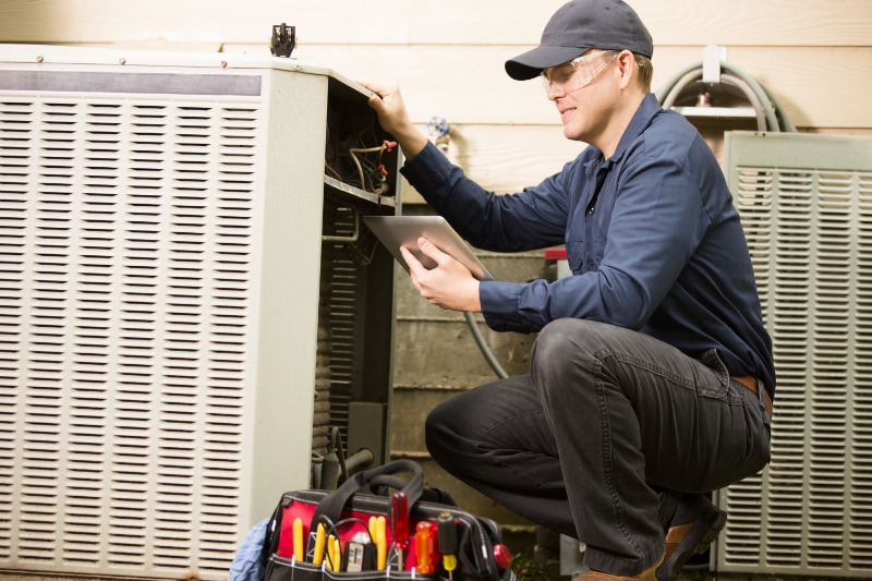 Repair man looking at ac unit.