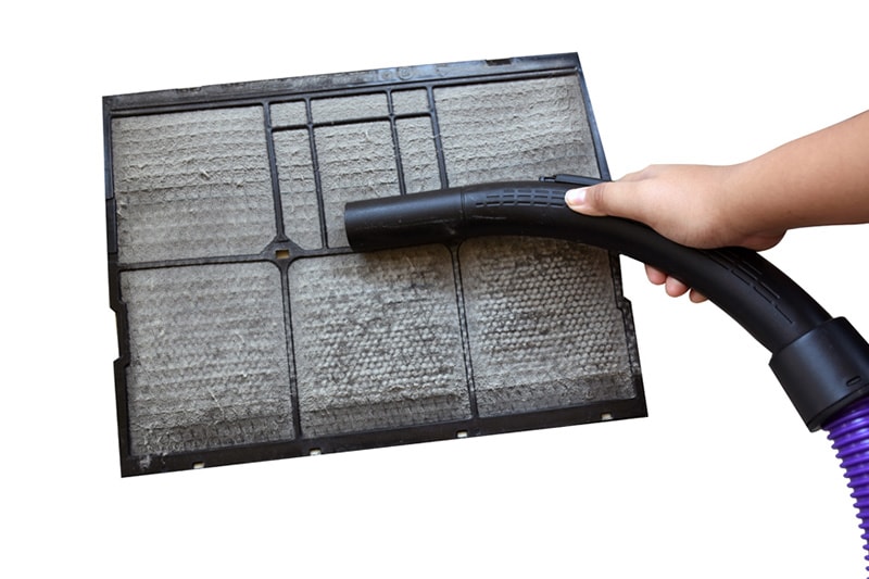 Vacuuming dirty air filter.